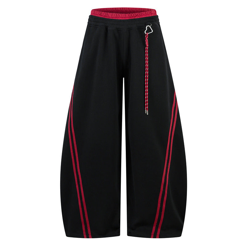 Black loose trousers with red side stripes and a red contrast waistband.