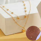 Gold-tone double-layer heart necklace displayed over a white block with a circular on-body inset.