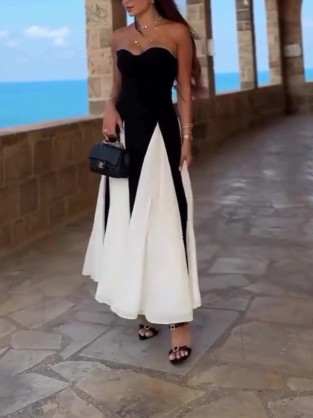 Black strapless dress with white skirt panels worn beside a seaside stone arcade.
