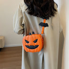 Orange jack-o’-lantern crossbody bag with black face and bat details on the strap, shown worn