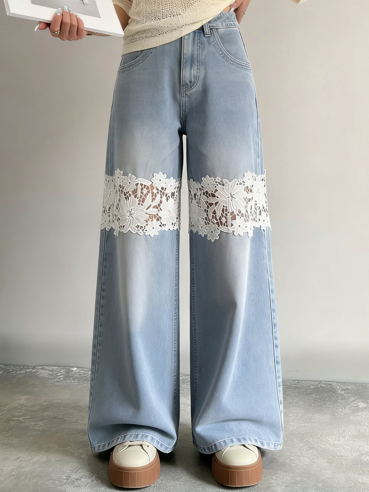 Front view of light-blue wide-leg jeans with white floral lace bands across both knees