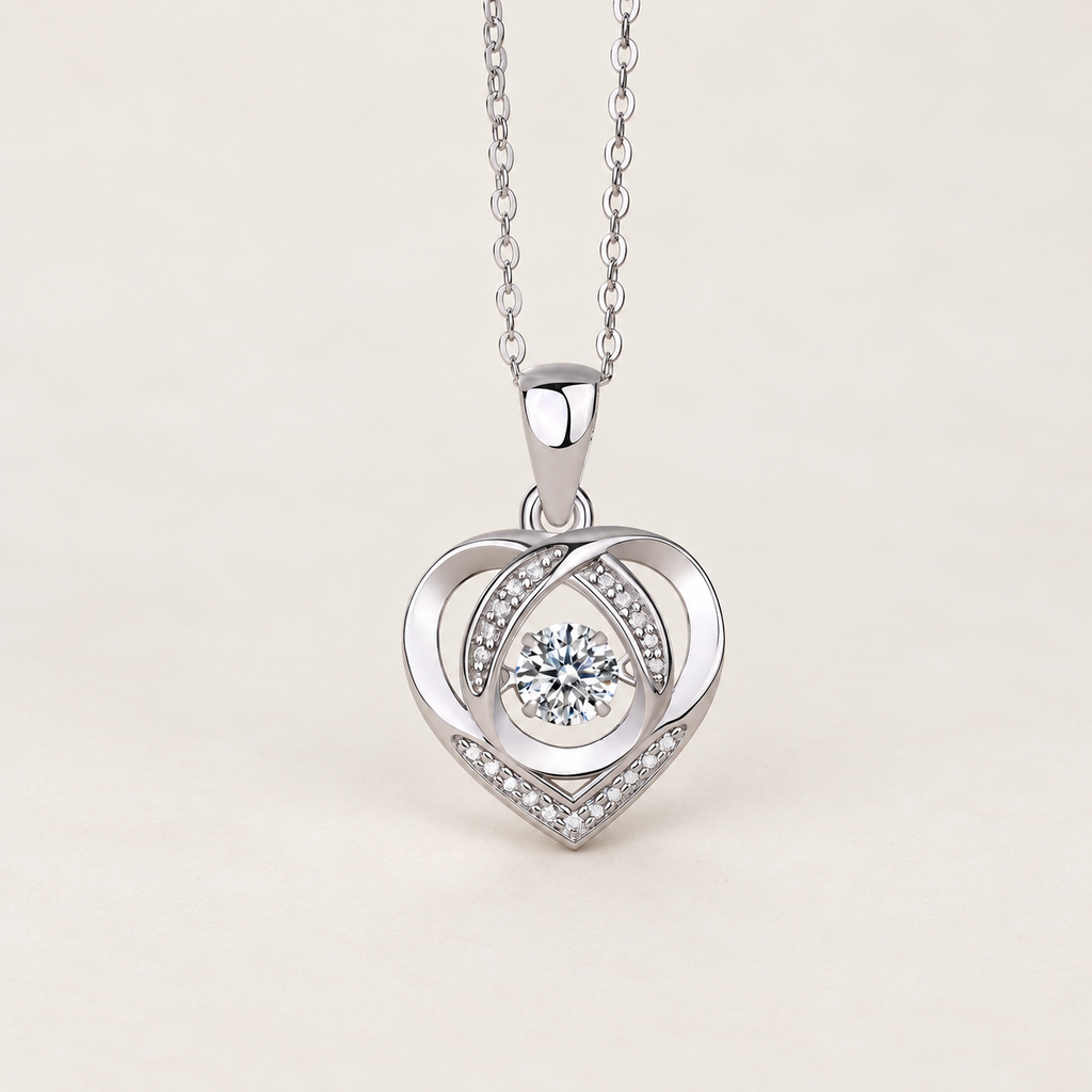 Silver-tone heart pendant necklace with a round clear center stone and small clear stones, on a warm ivory background