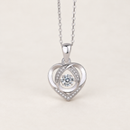 Silver-tone heart pendant necklace with a round clear center stone and small clear stones, on a warm ivory background