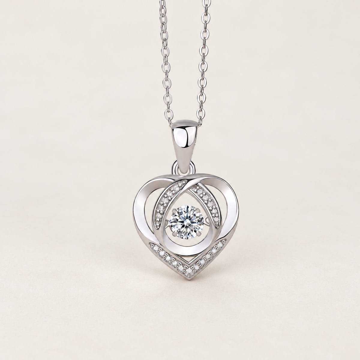 Silver-tone heart pendant necklace with a round clear center stone and small clear stones, on a warm ivory background