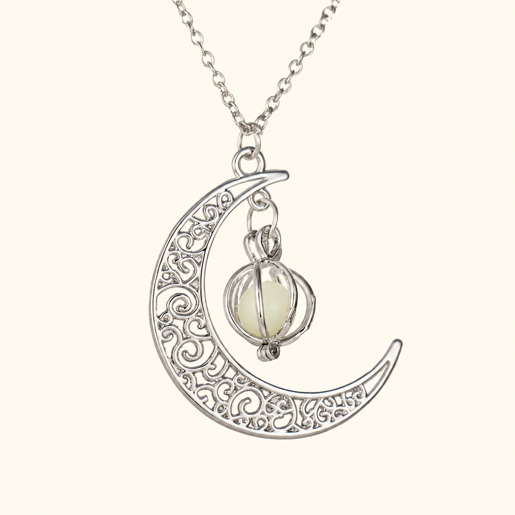 Silver-tone crescent pendant necklace with scroll details and a small caged pale orb on ivory