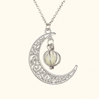 Silver-tone crescent pendant necklace with scroll details and a small caged pale orb on ivory