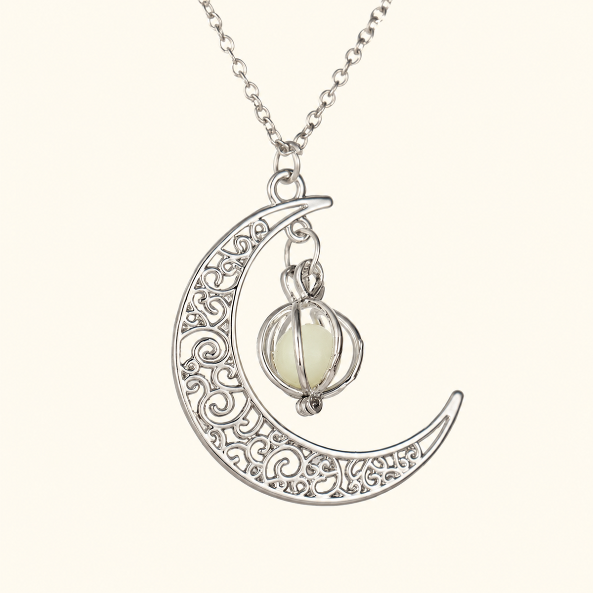 Silver-tone crescent pendant necklace with scroll details and a small caged pale orb on ivory