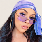 Woman wearing translucent purple rimless rectangular sunglasses and a blue-violet headscarf against a warm ivory background