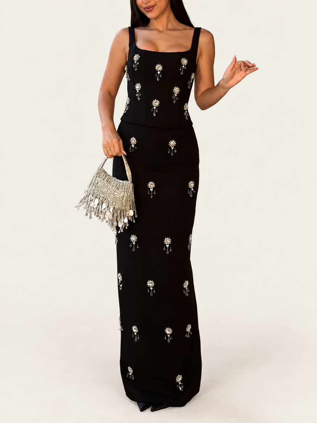 Model wearing a black beaded camisole top and matching maxi skirt against a warm ivory studio background