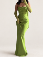 Model wearing a green draped maxi dress with matching long gloves against a warm ivory studio background