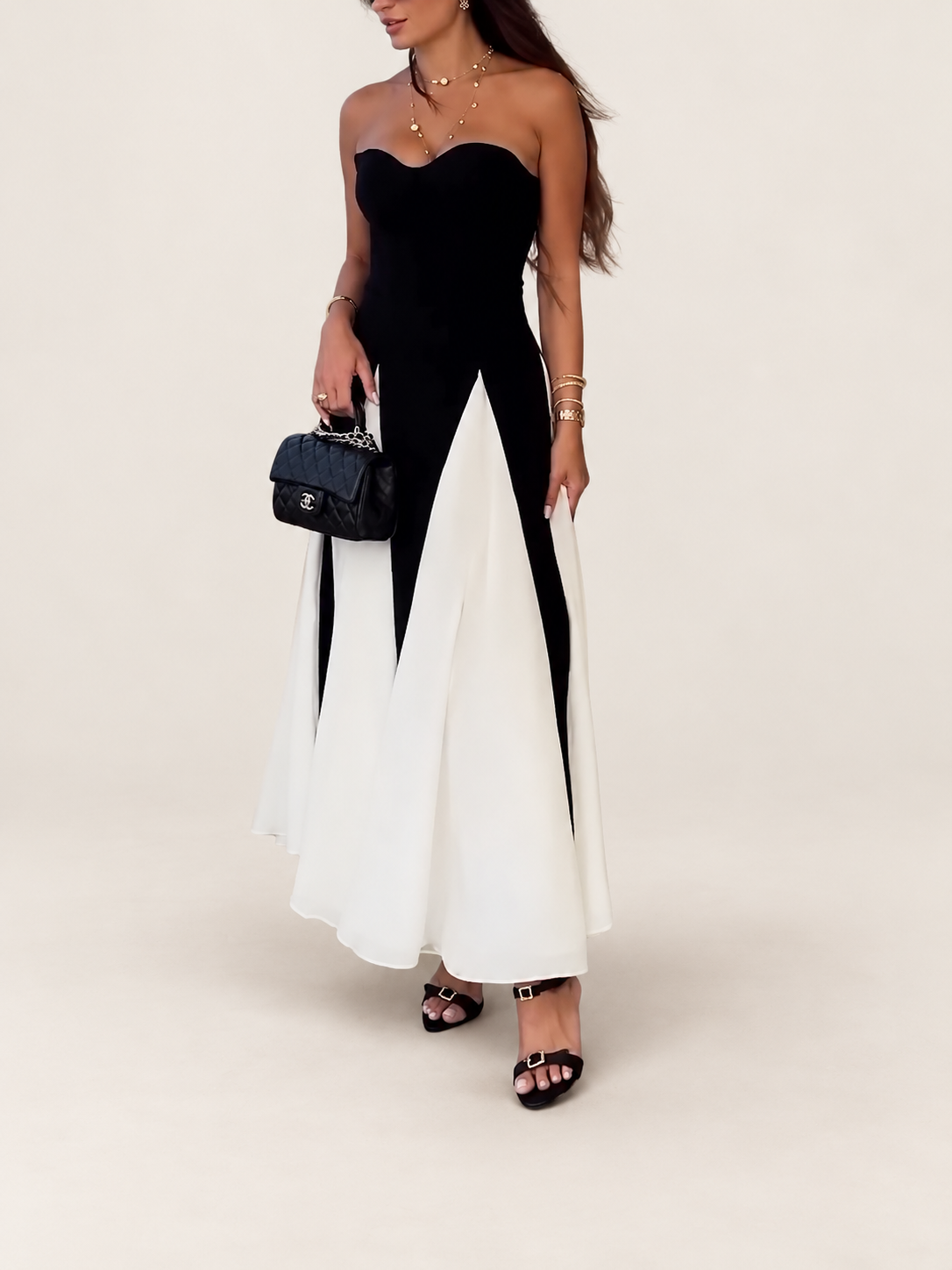 Model wearing a black and white strapless flared dress against a warm ivory studio background