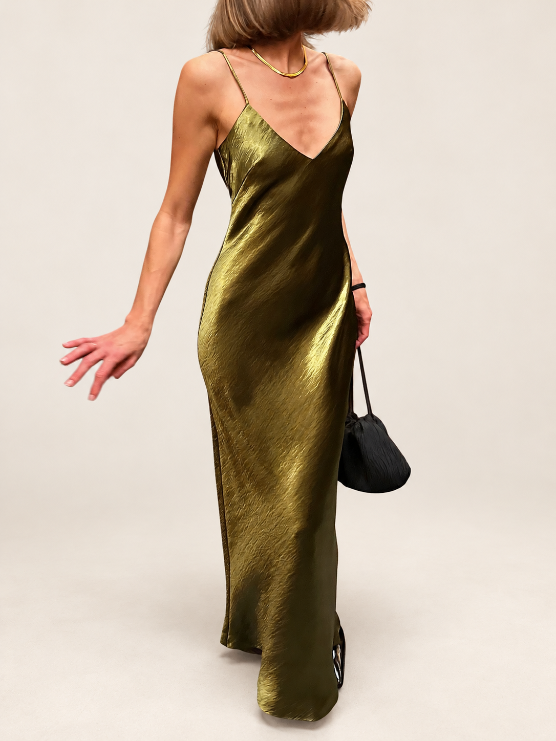 Model wearing an olive slip dress against a warm ivory studio background