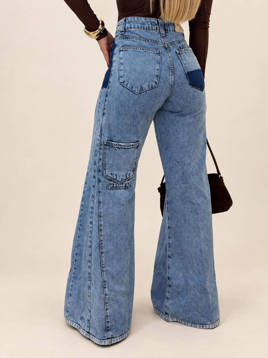 Rear view of light-blue wide-leg jeans with patch pockets, worn by a model against ivory