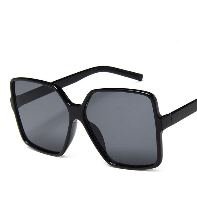 Black oversized angular sunglasses with grey lenses on a white background