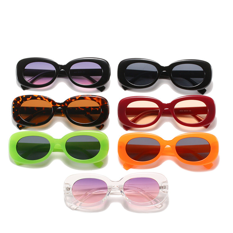 Seven separate colour options of oval sunglasses arranged together on white.