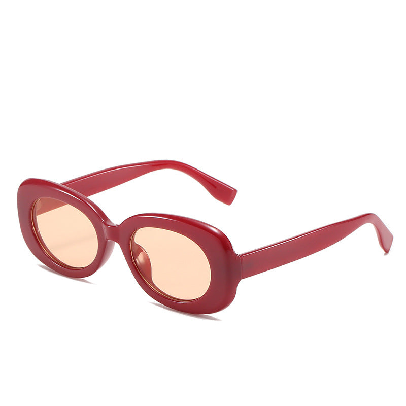 Red oval sunglasses with light-tinted lenses on white.