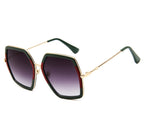 Oversized green and red geometric sunglasses with purple gradient lenses on a white background