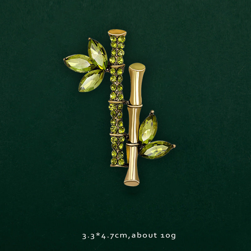 Bamboo-design brooch with green leaves on a dark green background