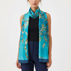 Lake-blue scarf with a flowering branch print worn around the neck