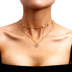 Gold-tone double-layer necklace with small heart charms and an open heart pendant worn against a white background.