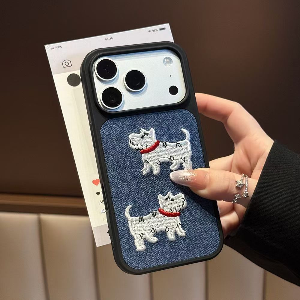 Phone case with a navy-blue textured panel and two white dog motifs with red collars, held in a hand