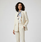Printed square scarf tied at the neck with a cream suit