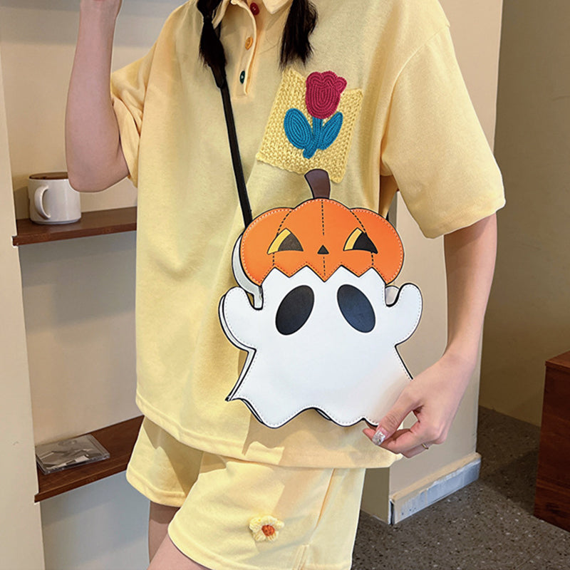 White ghost-shaped bag with an orange pumpkin hat worn across a yellow outfit.