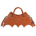 Brown bat-wing-shaped crossbody bag with spider-web stitching, handles and strap on white.