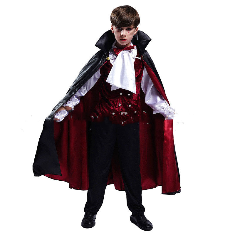 Child modeling a vampire costume with a black and red cape, white shirt, red vest and black trousers on a white background.