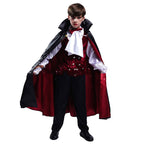 Child modeling a vampire costume with a black and red cape, white shirt, red vest and black trousers on a white background.