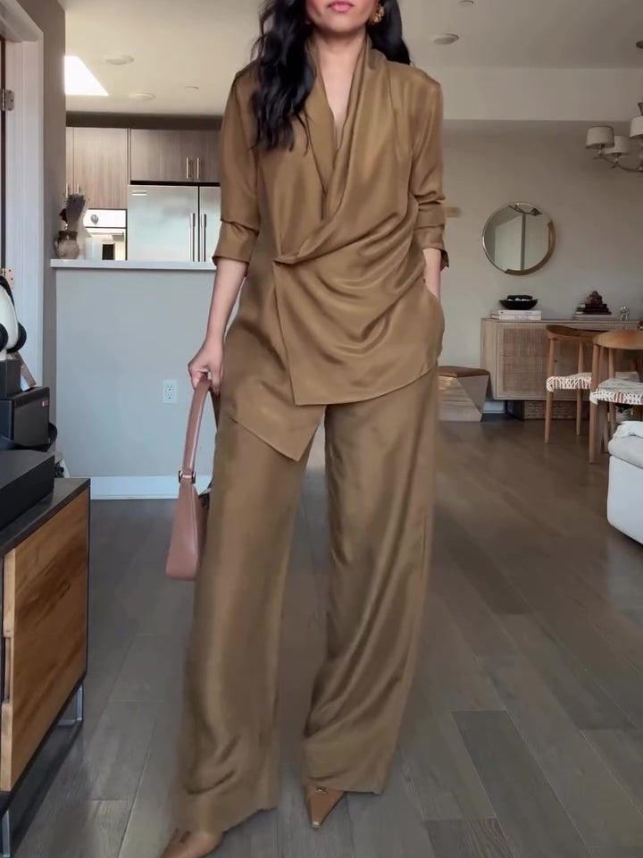Front view of a camel draped wrap blouse and wide-leg trouser set, worn indoors; handbag and shoes are styling accessories