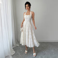 White halter A-line dress with a textured pattern, shown full length on a model beside a light curtain.