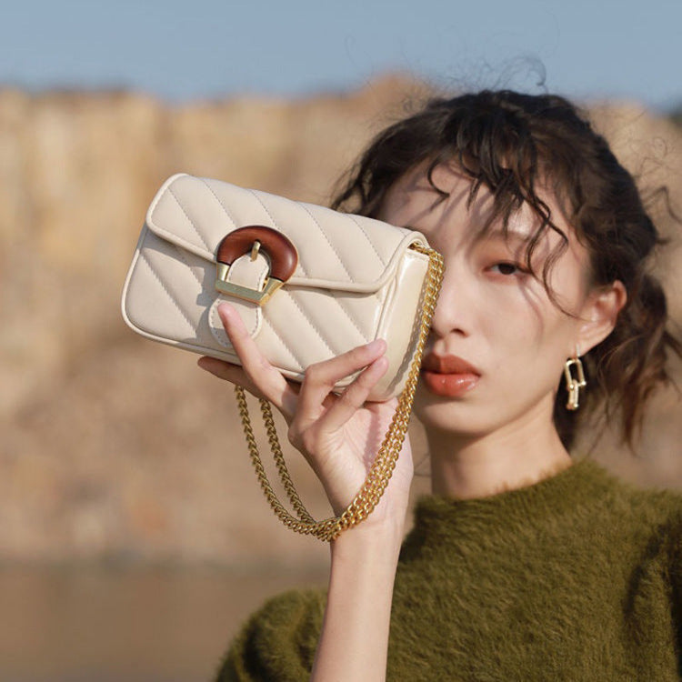 Beige Chain Detail Shoulder Bag held beside the face
