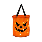 Orange jack-o'-lantern candy bag with angled eyes and a black handle, shown with glowing points on white.