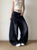 Model wearing washed black curved-leg jeans with metal eyelet rows and front pockets