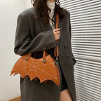Brown bat-wing-shaped crossbody bag worn across a dark green coat.