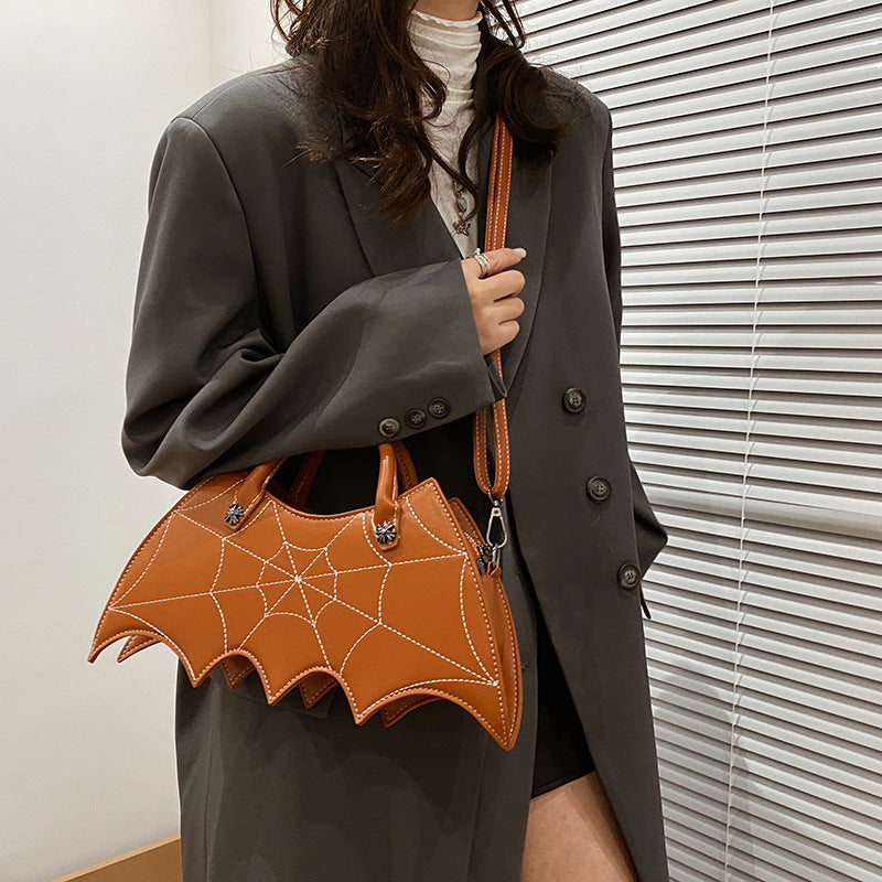 Brown bat-wing-shaped crossbody bag worn across a dark green coat.