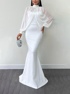 Model wearing a white dress with a beaded sheer high-neck long-sleeve top; clutch and jewellery are styling accessories