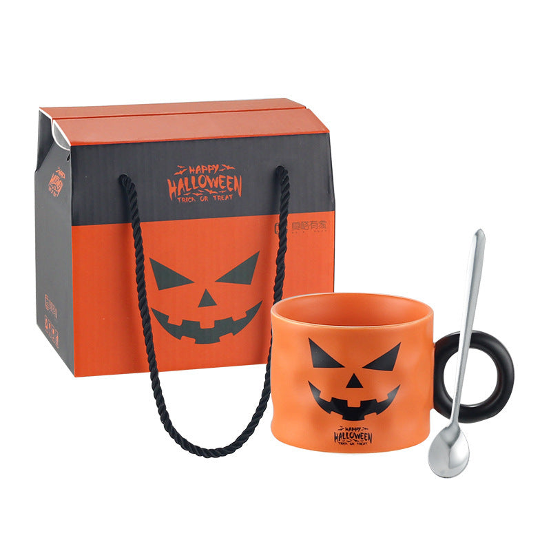 Orange pumpkin-face ceramic mug with black handle, dessert spoon and Halloween gift box