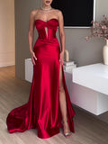 Full front view of a red strapless gown with a twisted bust, central cutout, high slit and trailing hem