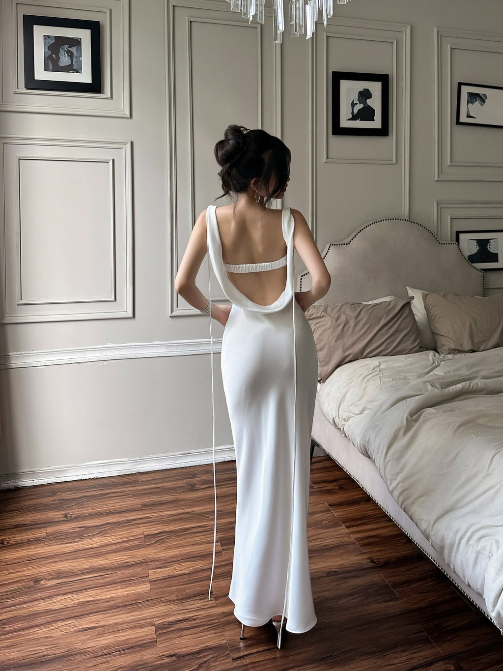Rear view of a white maxi dress with an open cowl back, horizontal strap and long side ties