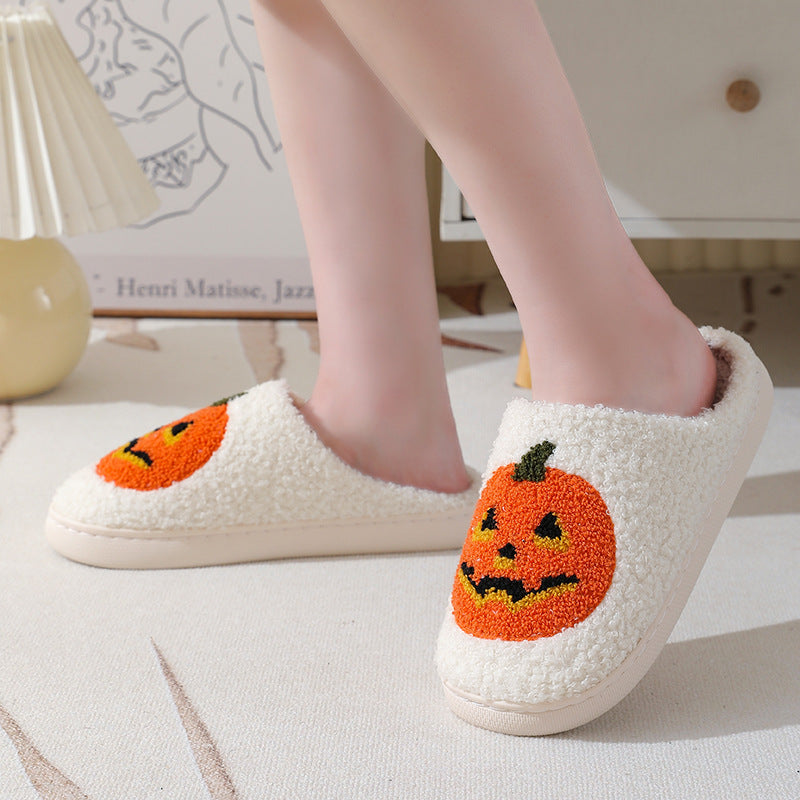 White pumpkin-face slippers with orange jack-o’-lantern artwork, shown worn as a pair