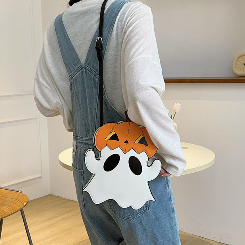 White ghost-shaped bag with an orange pumpkin hat worn at the side of blue overalls.