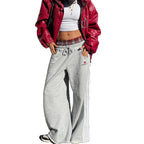 Grey wide-leg sweatpants with white side stripes and a drawstring waist, shown on a model.
