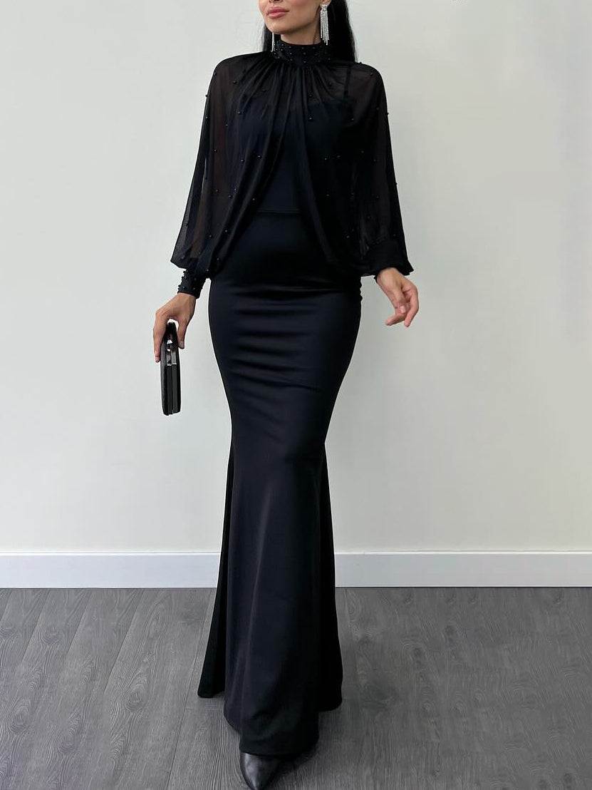 Model wearing a black dress with a beaded sheer high-neck long-sleeve top; clutch and jewellery are styling accessories