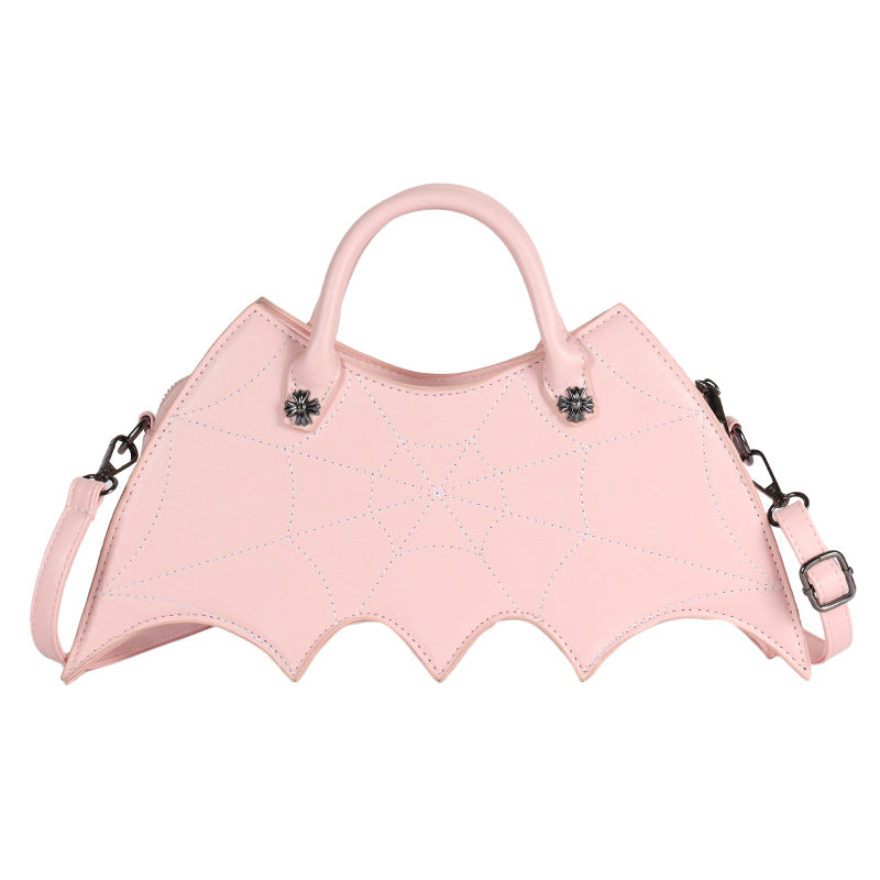 Pink bat-wing-shaped crossbody bag with spider-web stitching, handles and strap on white.