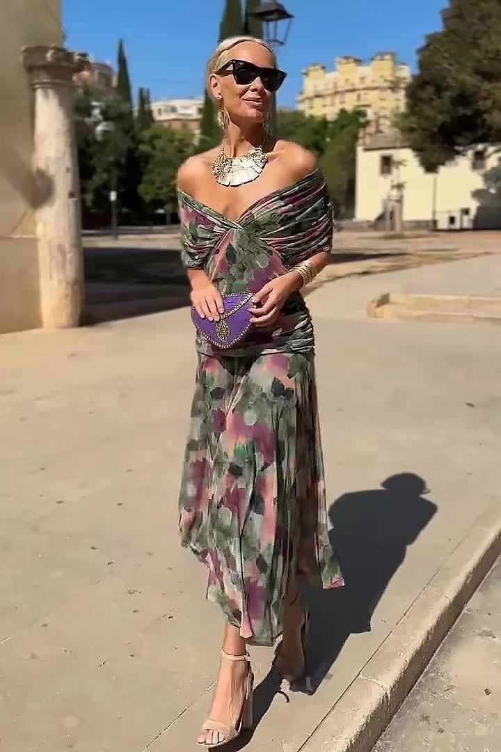 Green and pink printed long dress with a crossed neckline, shown worn outdoors.