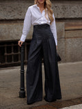 Dark high-waisted wide-leg jeans worn outdoors, showing the tall waistband and front pleats.