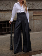 Dark high-waisted wide-leg jeans worn outdoors, showing the tall waistband and front pleats.