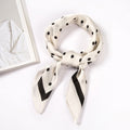 Beige scarf with black polka dots and a black border, shown knotted